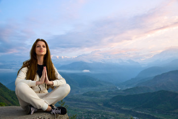Naklejka na ściany i meble Young beautiful woman meditating in The Himalayas at sunrise