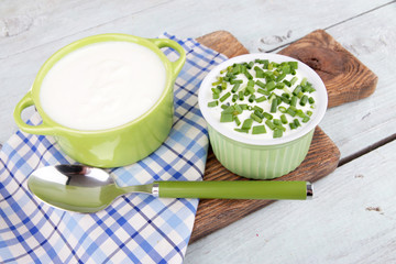 Green pan and plastic bowl of cream