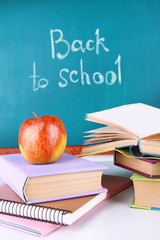 School supplies on table on blackboard background