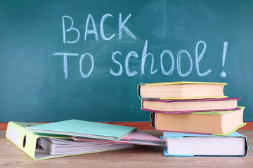 School supplies on table on blackboard background