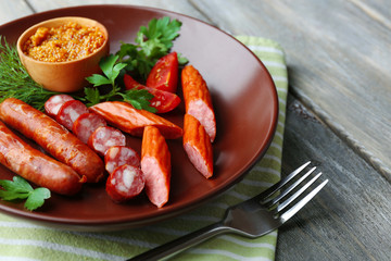 Assortment of tasty thin sausages on plate on wooden background