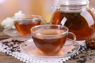 Teapot and cups of tea on table on light background