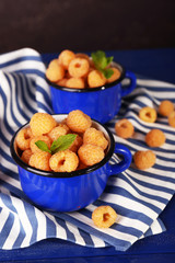 Yellow raspberries in dark blue mugs