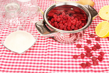 Red raspberries in metal pan, sugar, lemon and glass jars