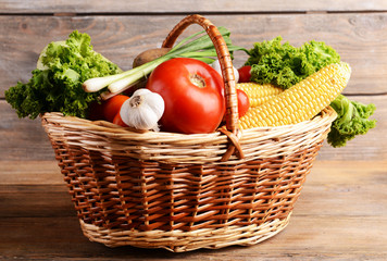Vegetables in wicker basket on wooden background