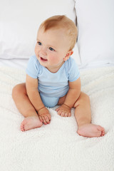 Cute baby boy on bed in room