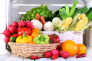 Vegetables in crate and in basket on white wooden box
