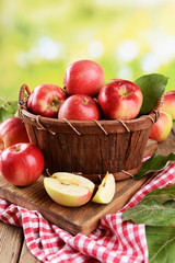 Sweet apples in wooden basket on table on bright background