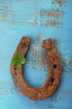Old horse shoe,with clover leaf, on wooden background