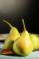 Fototapeta na wymiar Ripe tasty pears on wooden table, on dark background