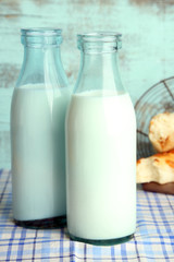 Retro bottles of tasty milk and bread, on table