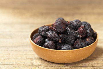 Black dried figs on a wooden surface