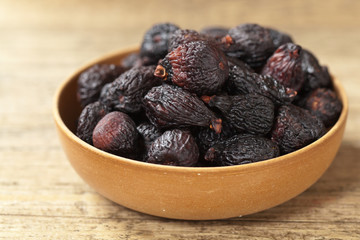 Black dried figs on a wooden surface