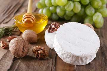 Camembert cheese, nuts, grapes and honey in glass bowl