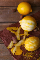 Lemons, nuts and grater on paper on wooden background