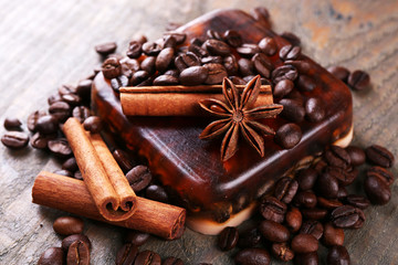 Organic soap with coffee beans and spices on wooden background