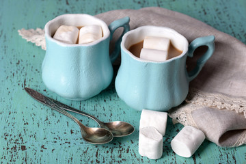 Cups of coffee with marshmallow and napkin on wooden table
