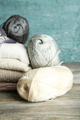 Knitting clothes and yarn on wooden background