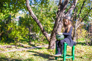 Naklejka premium Happy little girl in halloween costume with jack pumpkin.Trick