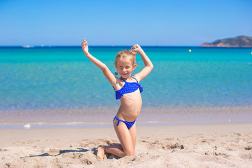 Fototapeta na wymiar Adorable little girl making wheel on tropical white sandy beach