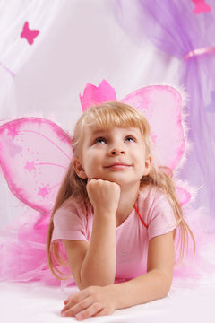 Princess girl in pink crown and butterfly wings making wishes