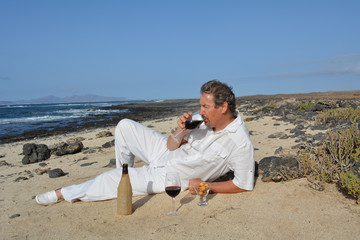 A man drinking red  wine on the tropical beach