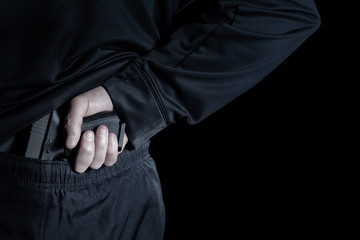 Back view of pistol being pull out of pants by male hand for gun control or rights 