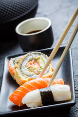 Sushi in a black ceramic eaten with chopsticks