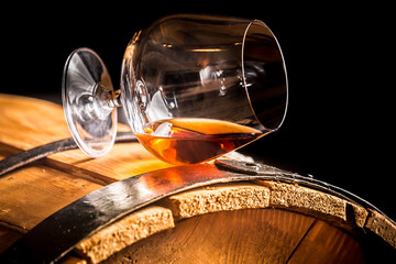 Obraz na płótnie Canvas Glass of cognac on the old wooden barrel