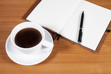 Open a blank white notebook, pen and cup of coffee on the desk