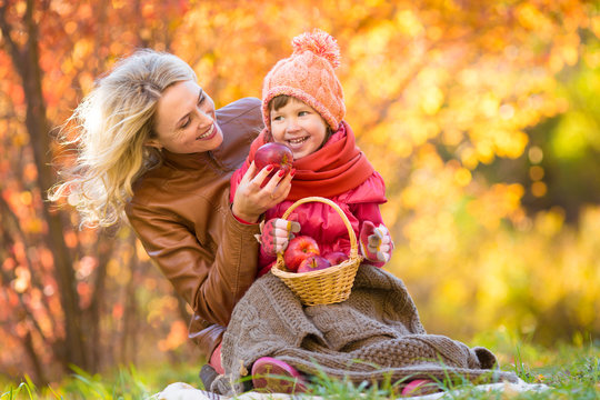Mother and kid making pinic together in autumn park.