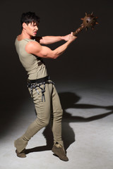 Strong young man in a costume is hit with a mace