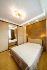 Modern bedroom with closet, large mirror and chandelier.