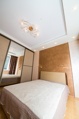 Clear bedroom with closet, large mirror and chandelier.