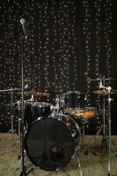 Drum set with microphones and cymbals in room with garland.