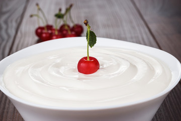 white bowl full of sour cream with cherry