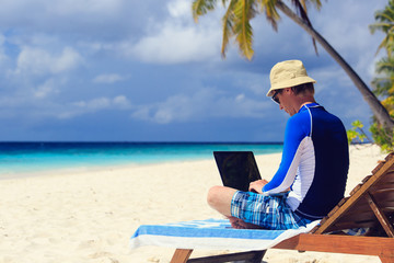 man with laptop on beach vacation