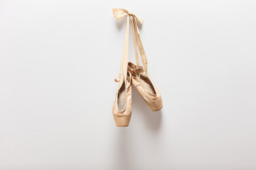 Pair of old ballet shoes hanging on a wall