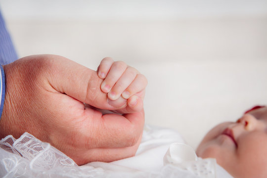 Baby holding daddies finger.