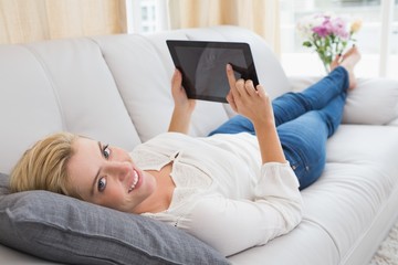 Beautiful blonde using tablet on sofa