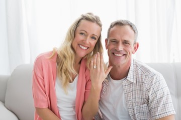 Happy woman showing engagement ring besides man