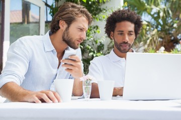 Two friends having coffee together with laptop