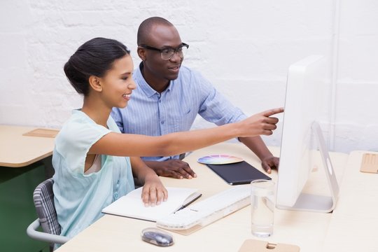 Woman showing something to her colleague on the laptop