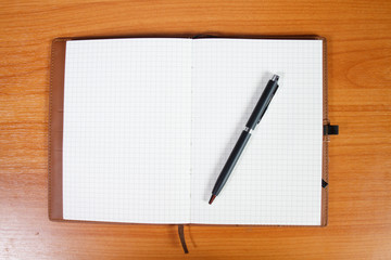 open notebook with passport and pen over wooden background
