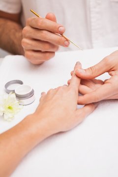 Manicurist painting a customers nails