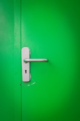 Metal door handle on green steel door