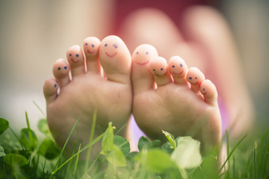 Little girl's feet with painted toes lying in grass