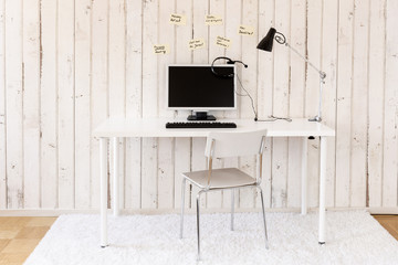 Home office with personal computer, headset and sticky notes on the wall