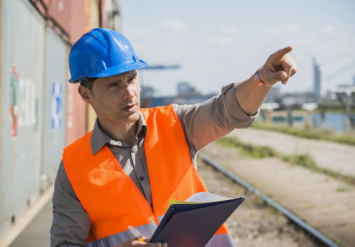 Portrait of man with blue safety helmet checking cargo containers