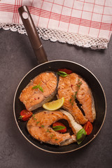 Fried salmon seak in pan with lemonq tomatto and aromatic herbs